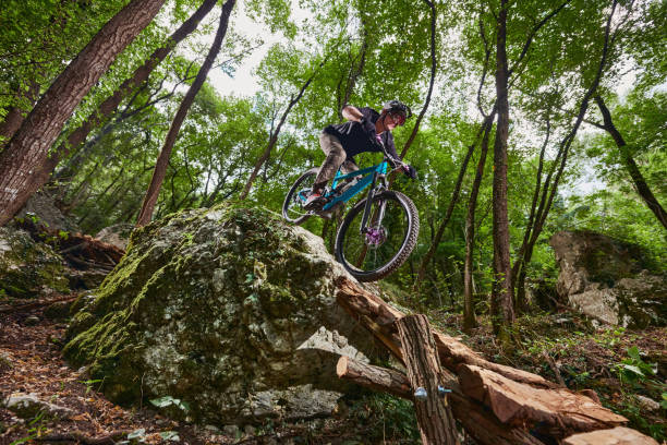 Enduro biker on a self-constructed challenging trail in the woods Enduro bike with full suspension and protective sports gear and equipment on a steep north face on a dirt path sports photography stock pictures, royalty-free photos & images