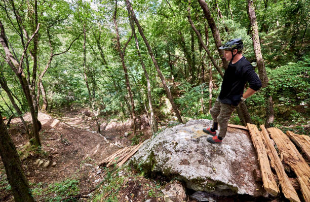 istock Enduro biker evaluating a challenging drop on a self-constructed trail in the woods 1349010313
