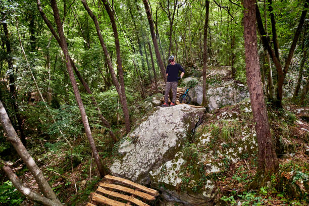 Enduro biker looking over a drop on a self-constructed trail in the woods