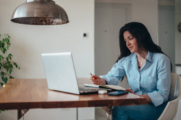 istock Beautiful businesswoman using laptop and a business planner while working in the office 1349010548