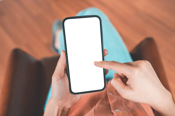 istock Woman using mobile smartphone with blank white screen on a sofa in living room. 1349011046