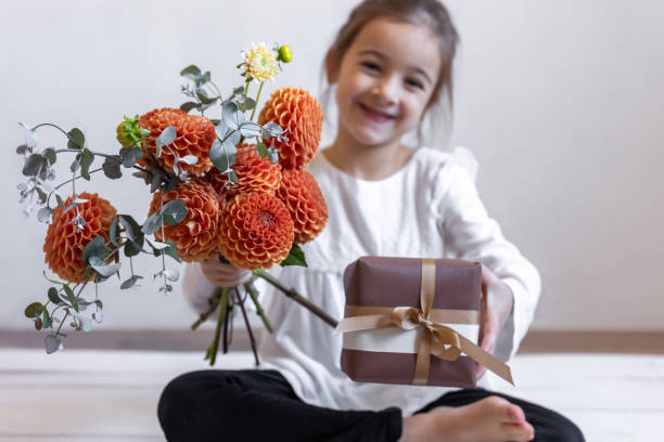 bambina con un bouquet di fiori di crisantemo e una scatola regalo. - small bouquet foto e immagini stock