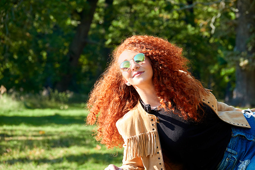 Red haired young beautiful woman with sunglasses enjoying summer sun
