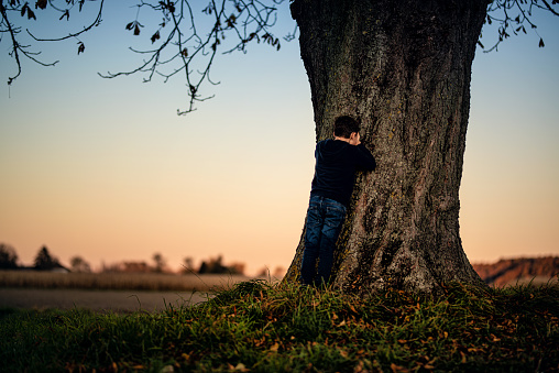 Austria. Young boy play hide and seek in the autumn evening sun.