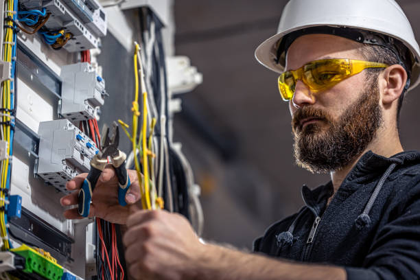A male electrician works in a switchboard with an electrical connecting cable. stock photo