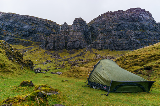 A tent camping in the middle of the green in front of rock formation of quiraing, Isle of Skye, Scotland