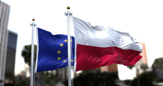 The flags of Poland and the European Union waving in the wind. On October 2021 polish Constitutional Tribunal issued that the Polish Constitution in some cases supersedes rulings by the EU court.