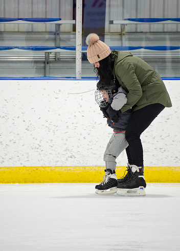 Mom holds toddler up while he attempts to learn how to skate