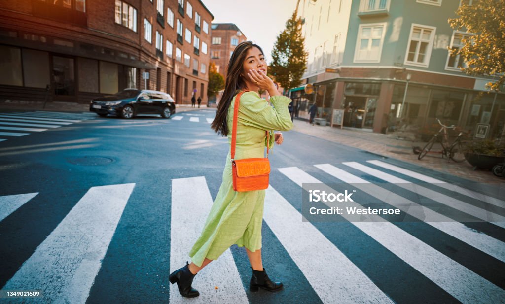 Young woman crossing road Model outdoors in city / street walking in a cross walk. Women Stock Photo