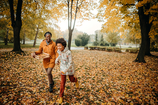 Hello september. happy young mother and daughter with autumn yellow leaves having fun time outdoors in the city park in autumn.
