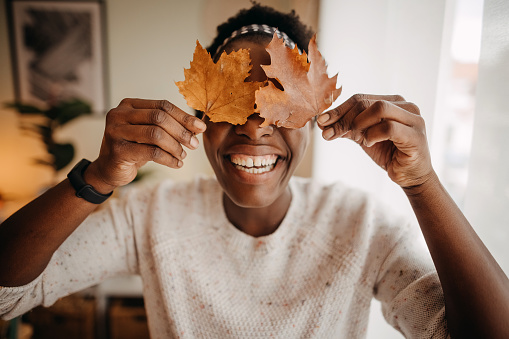 Smiling young female playing with autumn leaves