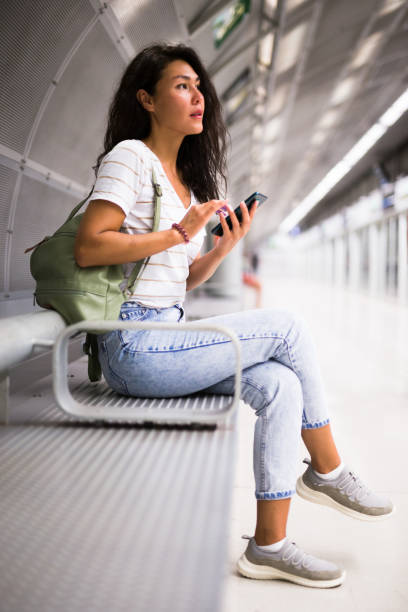istock Woman using smartphone while waiting for train in metro station 1349028369
