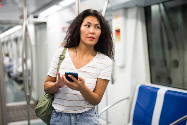 istock Woman with smartphone standing in metropolitan train 1349028376