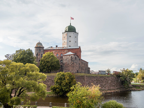 Medieval Vyborg Castle is Swedish-built fortress. White tower of Saint Olav with flag. Historical and architectural landmark in Russia.