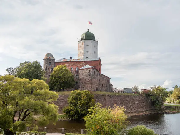 Photo of Medieval Vyborg Castle is Swedish-built fortress. White tower of Saint Olav with flag. Historical and architectural landmark in Russia.