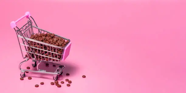 Cat or dog pet food in a shopping cart on a pink background. The concept of wholesale purchase of feed, pet store.