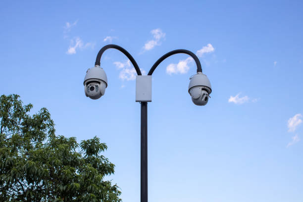 istock Surveillance cctv (closed circuit television) camera installed in public park on blue sky background for protection against crime, observation of people, control of observance of public order 1349037020