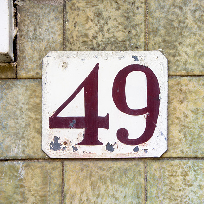 Weathered grunge square metal enameled plate of number of street address with number 29 closeup