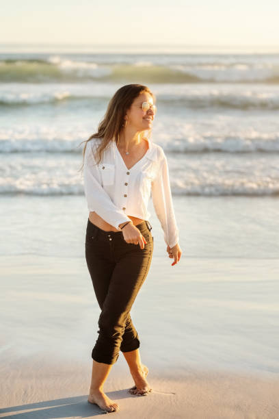 istock Happy woman in sunglasses walking on a sandy beach 1349040152