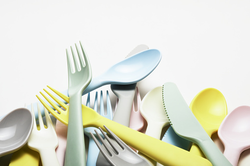 Colorful plastic cutlery, fork, spoon, knife on the white background with copy space