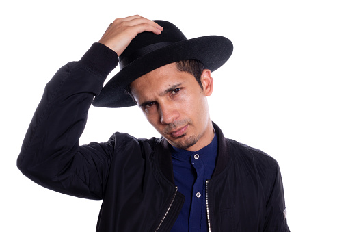 Man putting on black hat on white background. Young Latino man wearing hat.