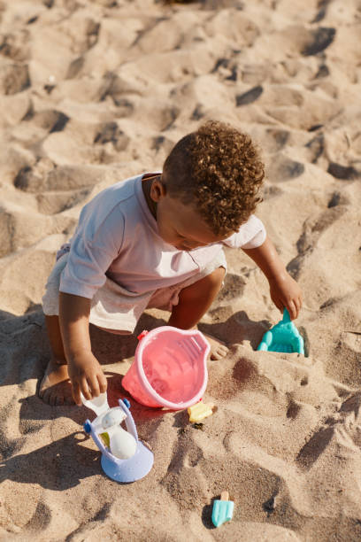 afroamerikanisches baby spielt im sand - lifestyles child beach digging stock-fotos und bilder