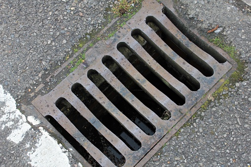 Metal grate in the road for rainwater drainage