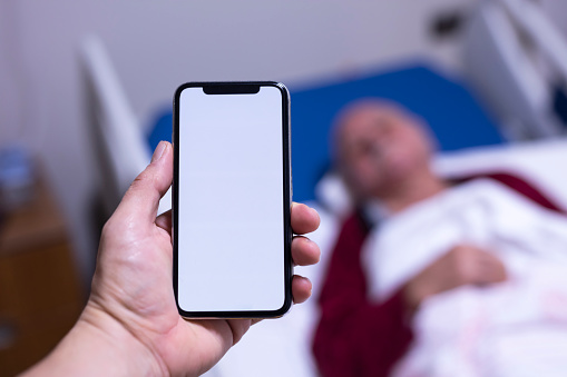 In the Hospital Doctor Holds Green Screen Mobile Phone, In the Background Patients Lies in Bed
