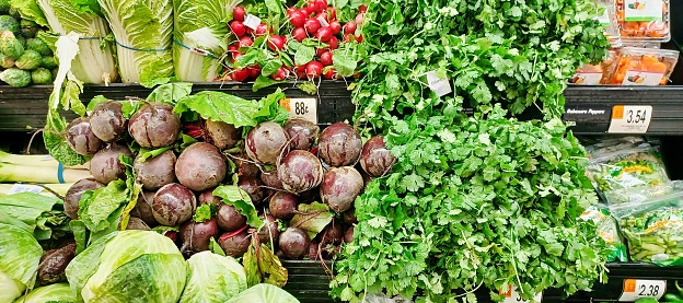 Fresh vegetables on display in a grocery market including beetroot, radish, cilantro, cabbage and wombok.