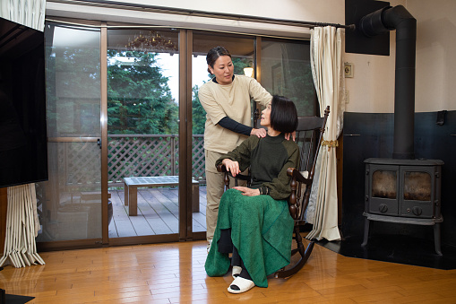 A Japanese female nurse giving a senior woman care at her home.