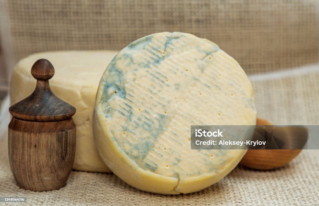 stilton cheese with blue mold still life with round stilton cheese in the ripening process and a wooden salt shaker Stilton Cheese Stock Photo