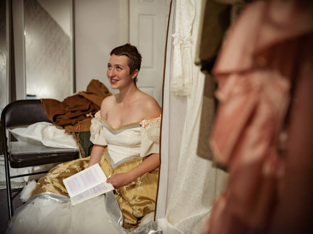 Actress in period costume in dressing room Young Actress in period costumes in dressing room. Getting ready for stage performance. Last minute adjusting of make up, and hair. Interior of dressing room of Theatre building at night. stage actress stock pictures, royalty-free photos & images