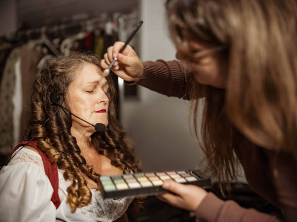 Mature Actress in period costume doing make up Portrait of Mature Actress in period costume doing make up. Interior of Theatre dressing room at night. actress headshot stock pictures, royalty-free photos & images