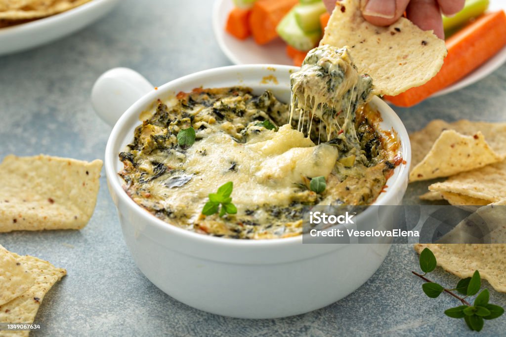 Artichoke spinach dip Artichoke spinach dip in a baking dish with a cheese pull Dipping Sauce Stock Photo