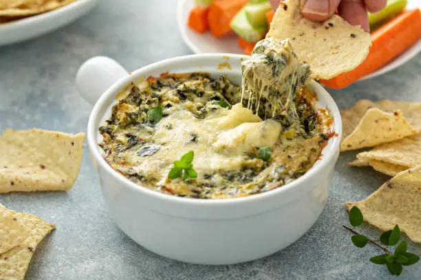 Artichoke spinach dip in a baking dish with a cheese pull