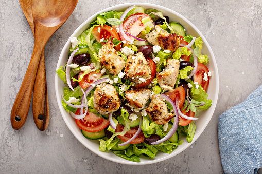 Greek salad with vinaigrette dressing topped with grilled chicken souvlaki