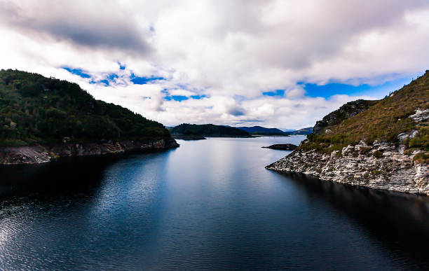 a beautiful environment with deep, dark blue coloured water highlighted by the reflection of the clouds overhead is the result of a hydroelectricity dam in tasmania. - mountain reflection non urban scene moody sky imagens e fotografias de stock