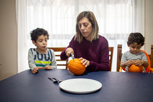 Mother and children cutting pumpkin for halloween