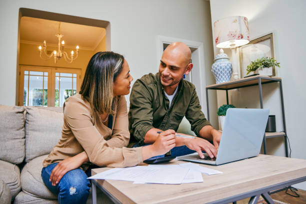 shot of a young couple reviewing their finances while using their laptop - electronic banking imagens e fotografias de stock