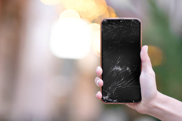 istock Broken glass on the phone screen. Broken phone in a woman's hand. Blurred evening lights background 1349080749