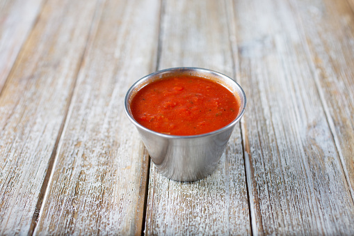 A view of a condiment cup of marinara sauce.