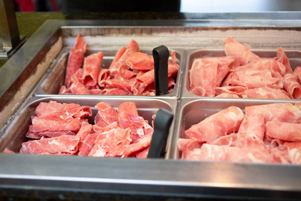 Group of people picking food (grilled meat and salads) from a buffet table. Unrecognizable Caucasian adults, both female and male.