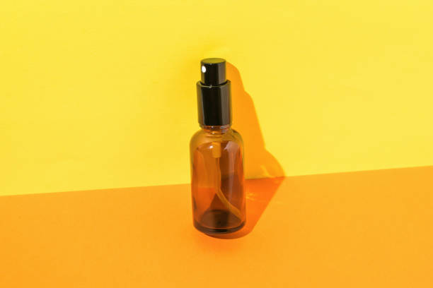 istock Glass spray bottle in bright light on orange and yellow background. 1349087848
