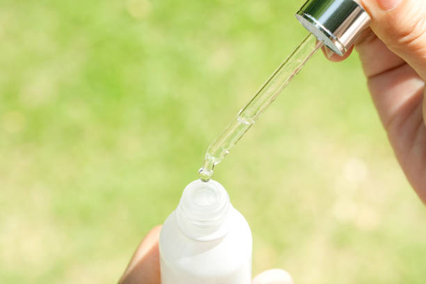 Dropping serum collagen moisturizer of face into clear yellow bottle soft light background. Protector skin Treatment facial essence oil, Vitamin C. Beauty and spa Concept