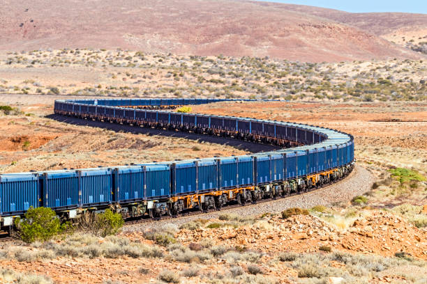 istock Long train of blue containers for iron ore travelling through harsh red stony desert terrain 1349090962