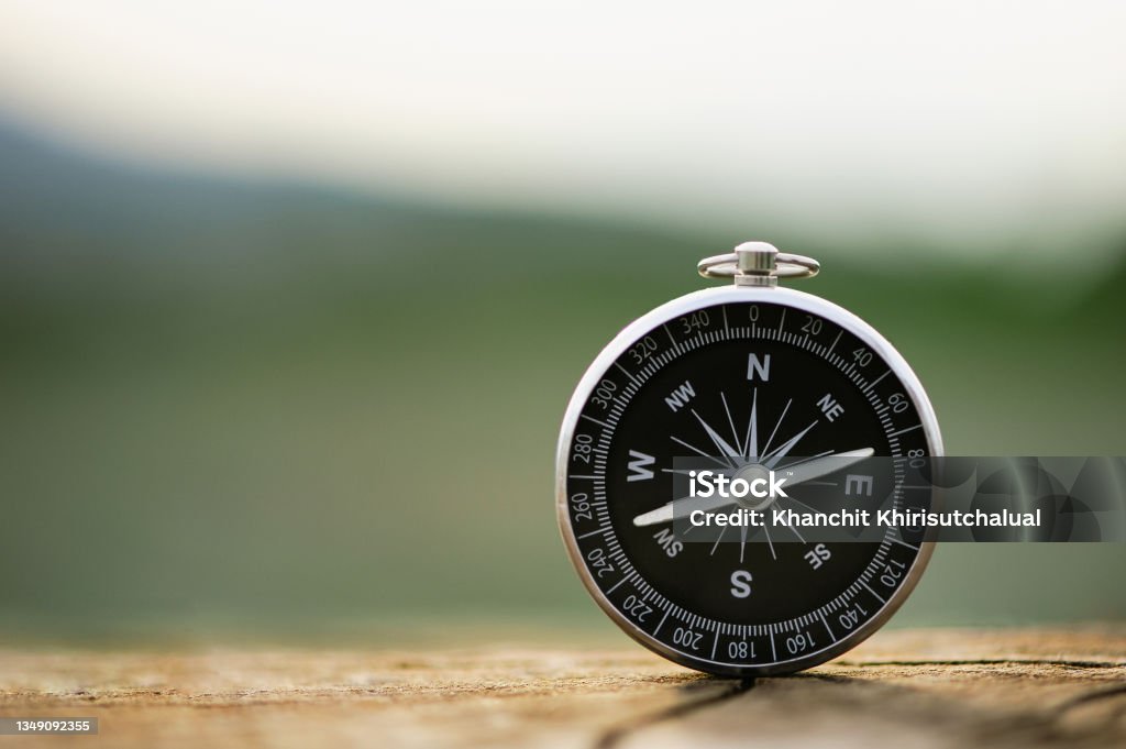 Classic compass on a wooden vintage with a green background. compass for a symbol of tourism with compass, travel with a compass, life direction concept. Navigational Compass Stock Photo
