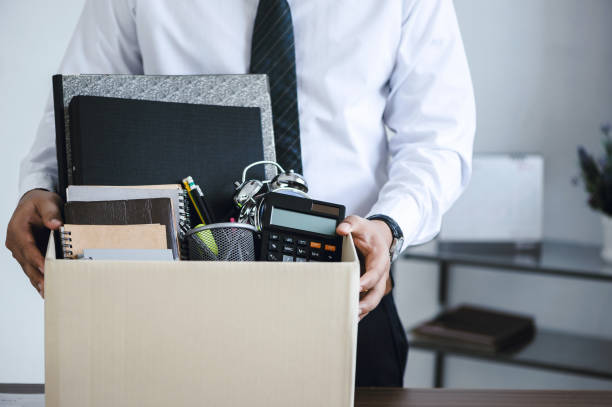 Businessmen hold boxes for personal belongings and resignation letters for resign by the desk in the office for changing and resigning from work concept for quit or change of job stock photo