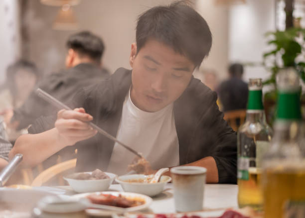A Asian man drinks drinking in beef hot pot store