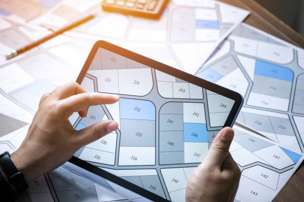 a man searching building plot on a cadastral plan to choose and buy a building plot for house construction on a digital tablet - land issues imagens e fotografias de stock