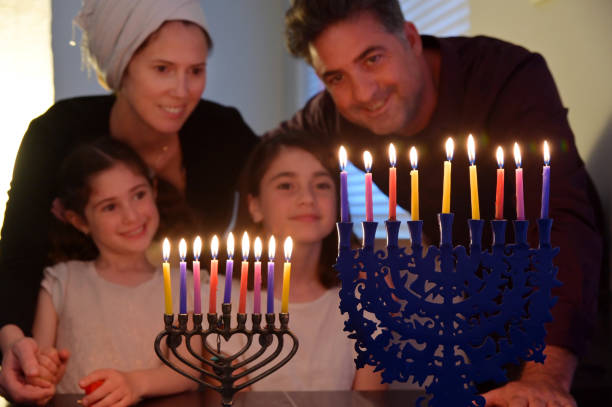 ハヌカ��ユダヤ人の休日祭りの8日間にカンデラブラムを見ている家族 - 6 11 months ストックフォトと画像
